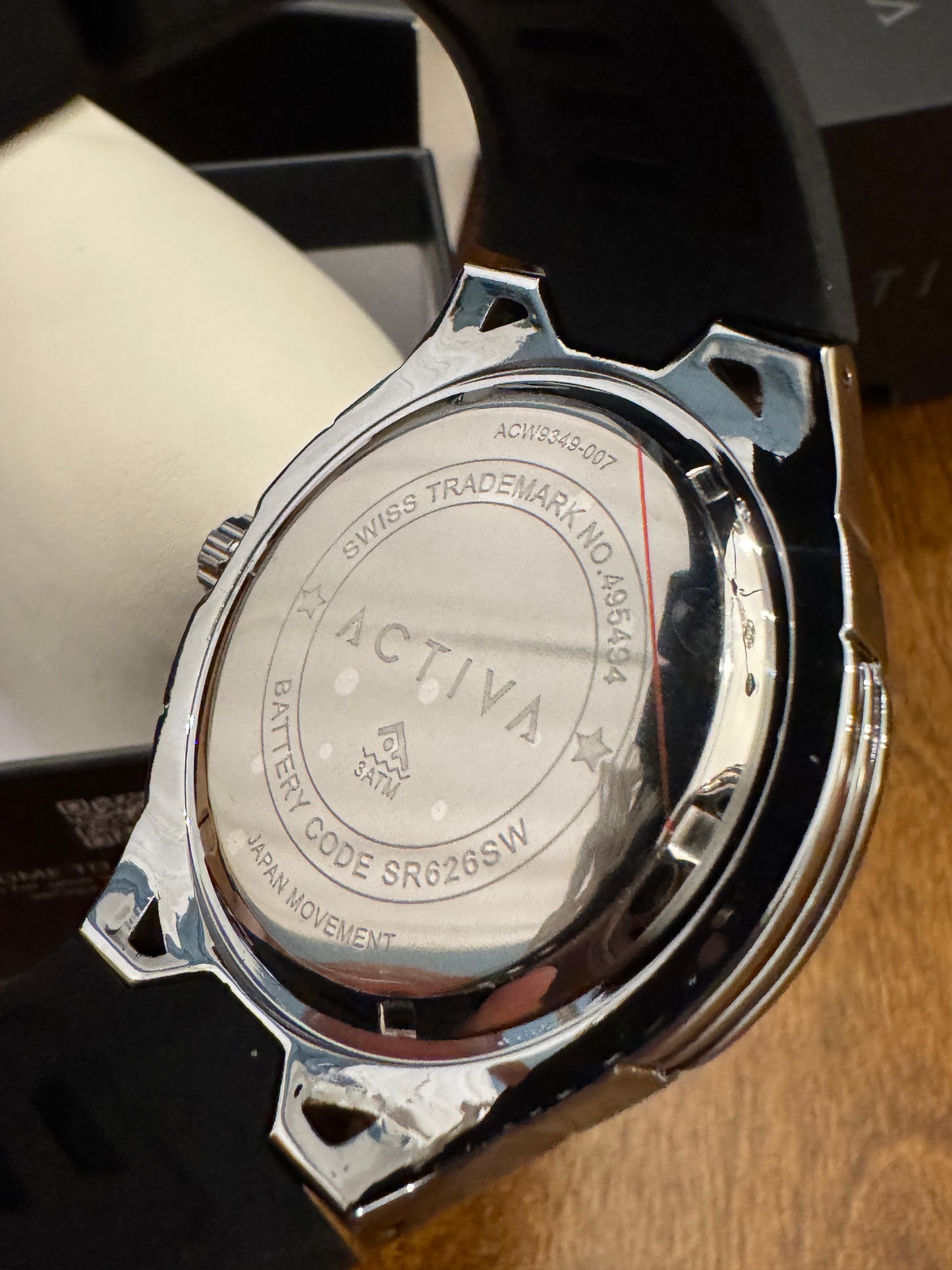 Close-up of a watch case with 'Activa' branding on a wooden surface