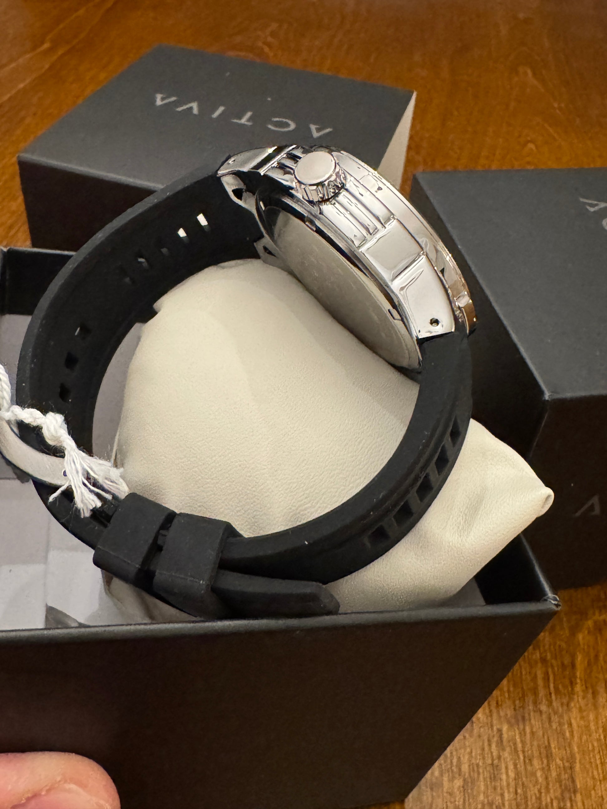 Watch with black strap in an open box on a wooden surface